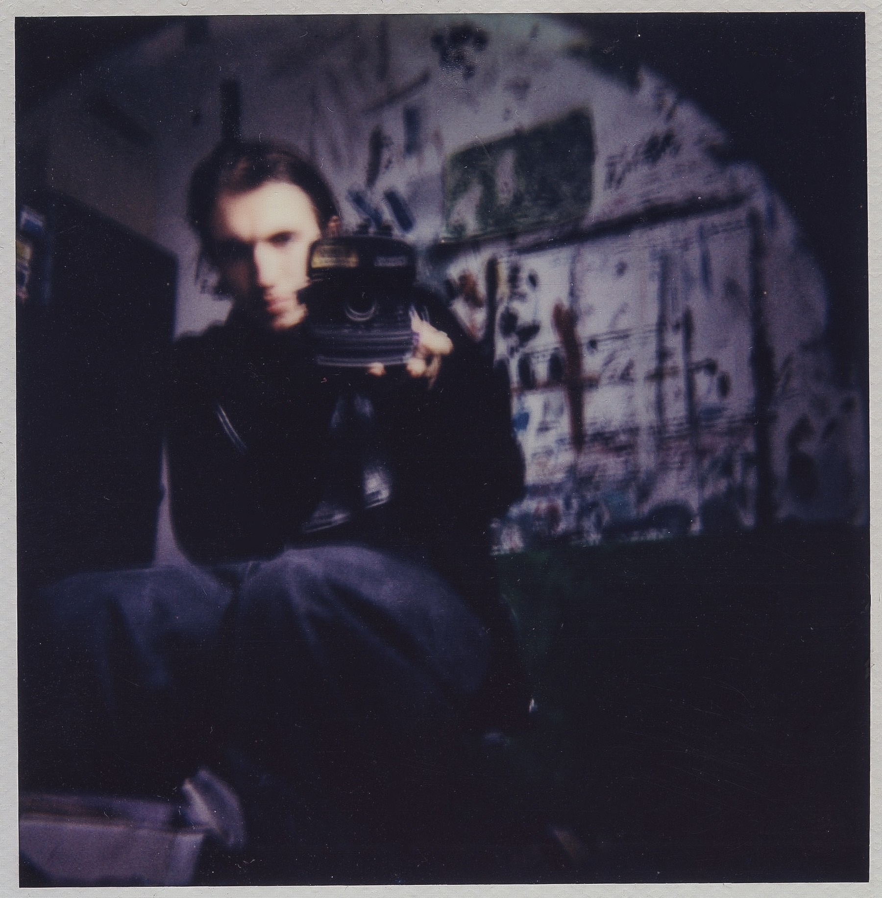 Polaroid-style self-portrait of Saul Michael holding a camera in a studio
